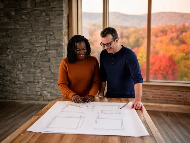 Two business partners smiling over a pencil floor-plan sketch on a wooden table